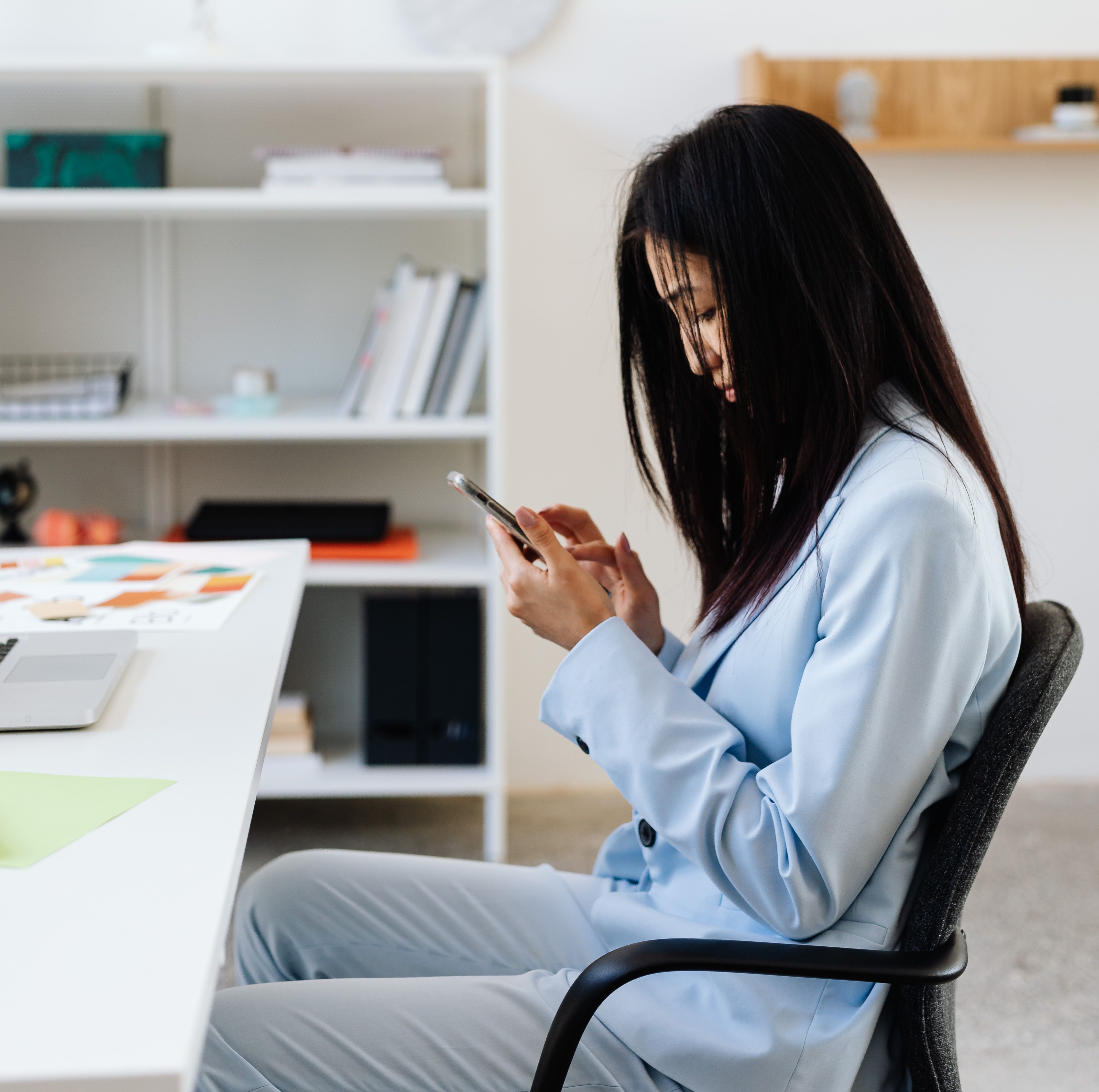 Woman distracted by her phone at her desk